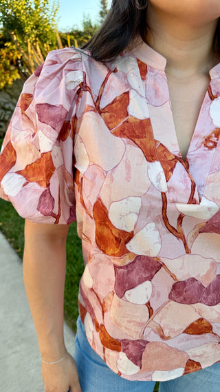 Woman wearing a pink floral blouse with blue jeans. 
