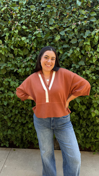 Woman wearing a brown sweater and blue jeans.