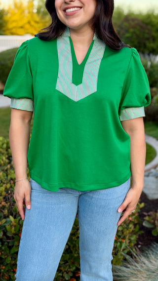 Woman wearing a green blouse with a white collar.