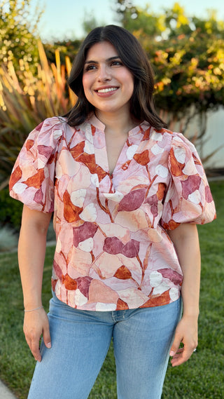 Woman wearing a floral blouse with blue jeans.