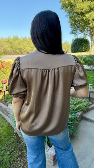 Woman wearing a burgundy V-neck blouse with ruffled sleeves 