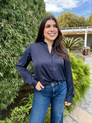 A woman wearing a brown long sleeve button-down shirt and blue jeans.