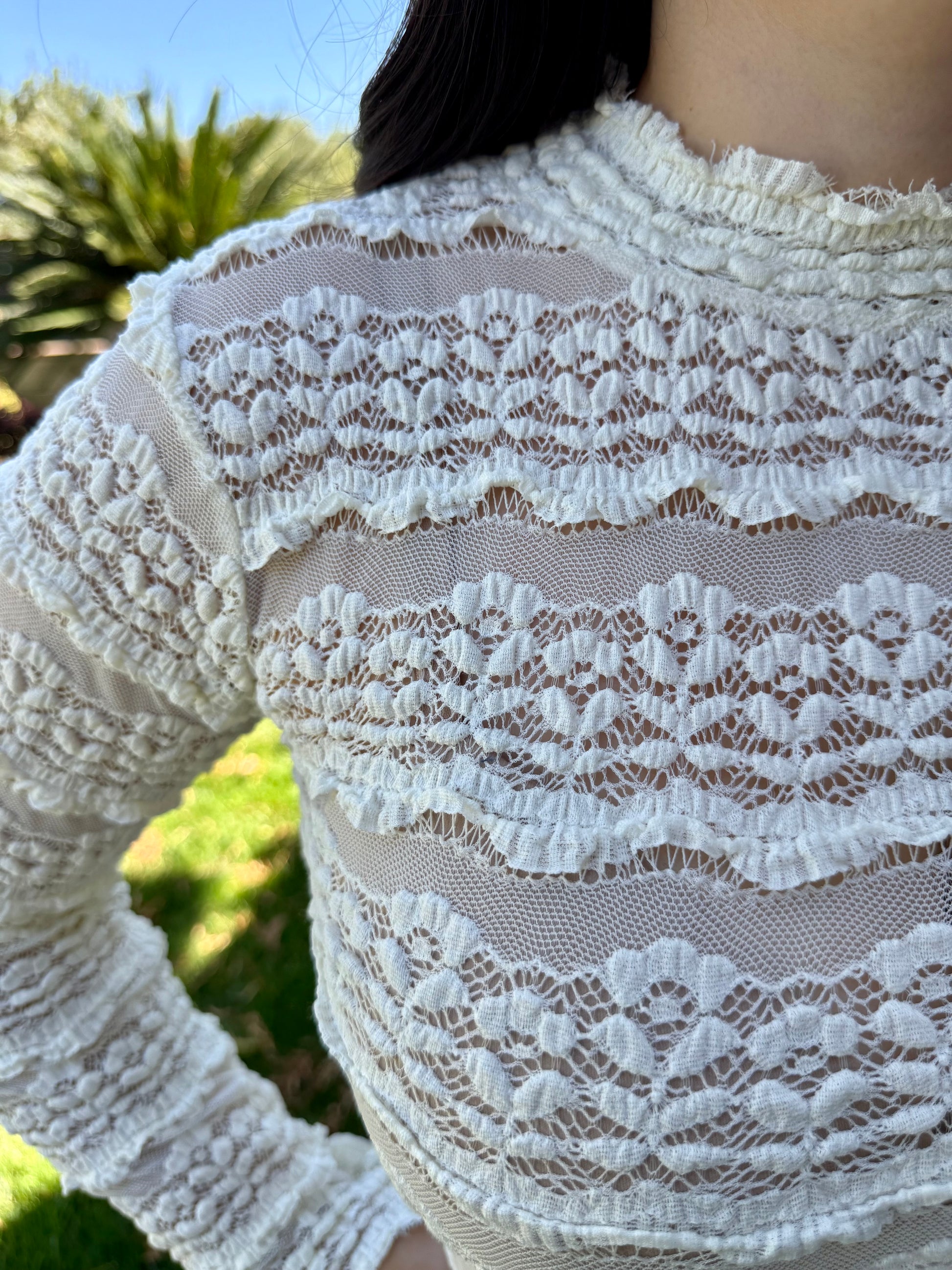 Close-up of a white lace garment with a blurred outdoor background