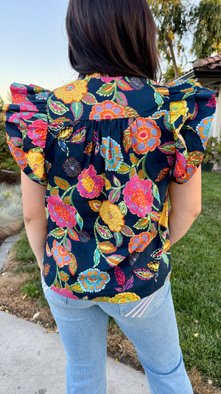 Woman wearing a floral blouse with light wash jeans.