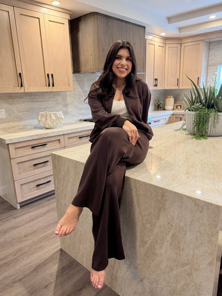 Woman sitting on a kitchen counter wearing a brown outfit.