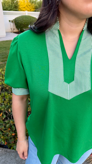 Woman wearing a green blouse with a white collar.