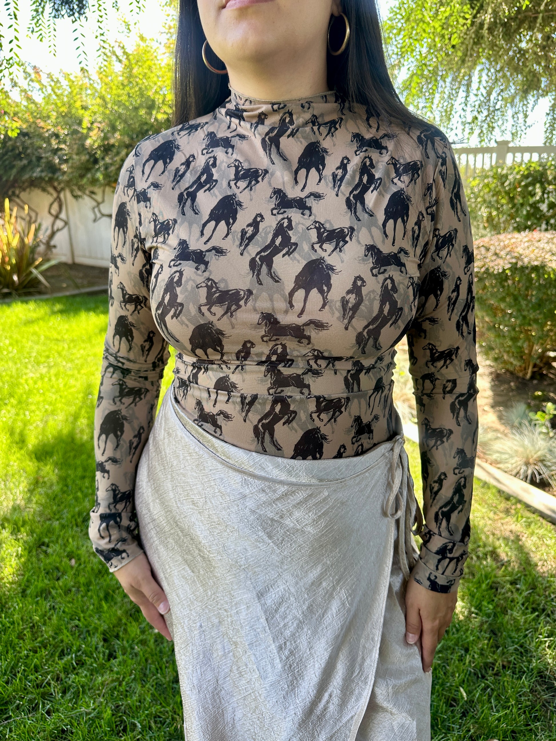 Person wearing a long-sleeve top with horse pattern outdoors