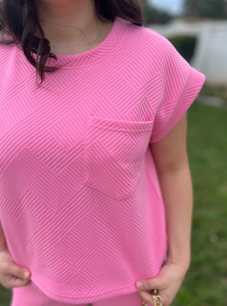 A woman wearing matching bright pink lounging top and pants. 