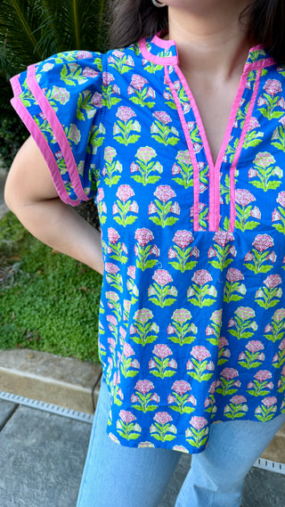 Woman wearing a colorful top with floral pattern and blue jeans.