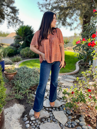 A woman wearing dark wash jeans with gold 7 stitching, showing the back pocket and the seam detail.