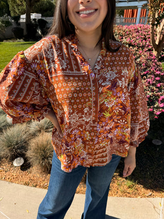 A woman wearing a 3/4 puffer sleeve op with a button down detail and floral pattern. 