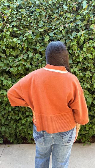 Woman wearing a brown sweater and blue jeans.