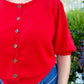 Red sweater with buttons worn with blue jeans