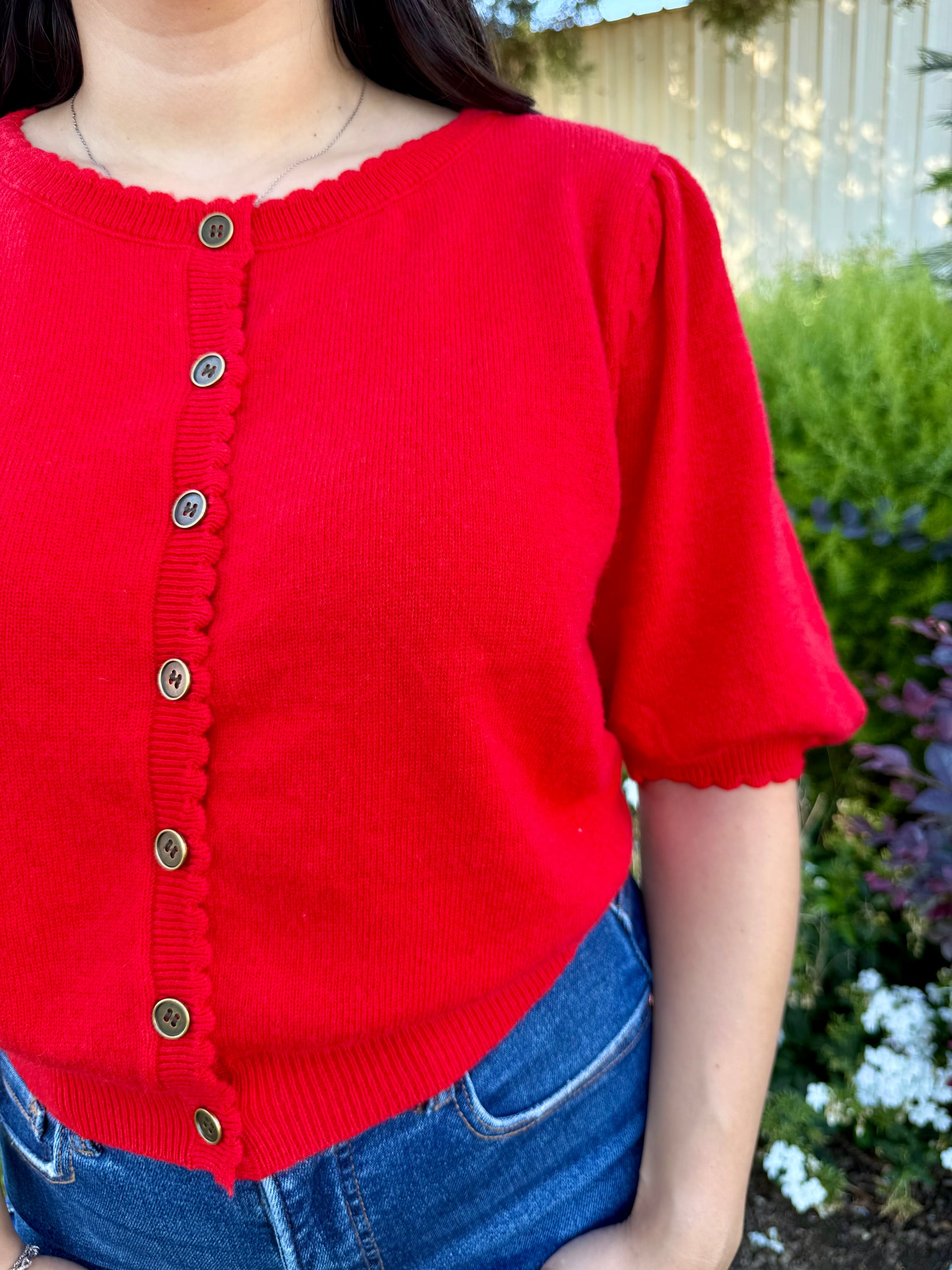 Red sweater with buttons worn with blue jeans