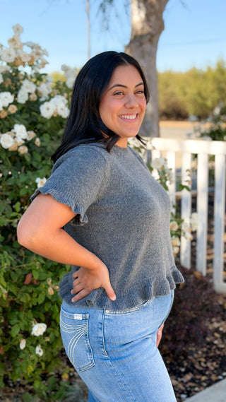 Side view of charcoal gray ruffle hem short sleeve sweater showing the relaxed, slightly cropped fit