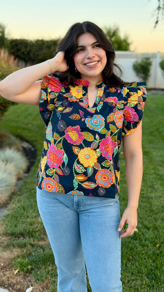 Woman wearing a floral blouse with light wash jeans.