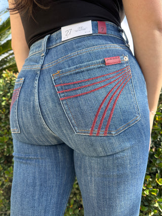 A woman wearing dark blue jeans with a red 7 stitched on the back pocket. 