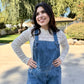 Woman wearing a light sweater and jeans standing outdoors on a sunny 