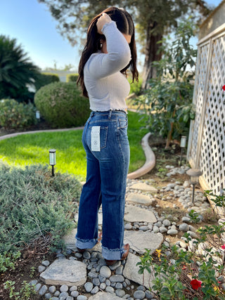A woman wearing dark high waisted wide leg jeans with boots. 