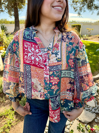 A woman wearing a patchwork 3/4 bubble sleeve blouse with blue jeans.