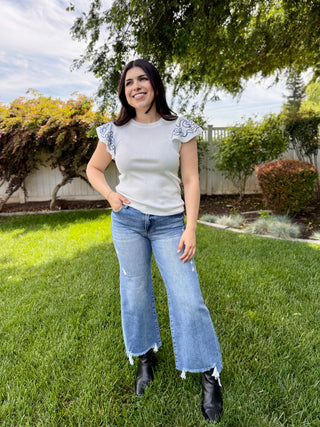 A woman wearing medium wash jeans that are cropped at the bottom. 