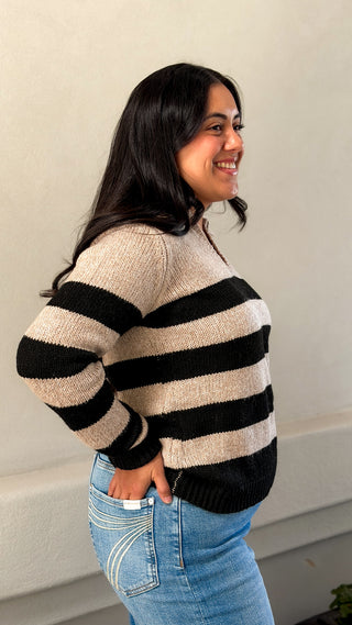 Side view of a women's black and cream striped collared sweater with jeans