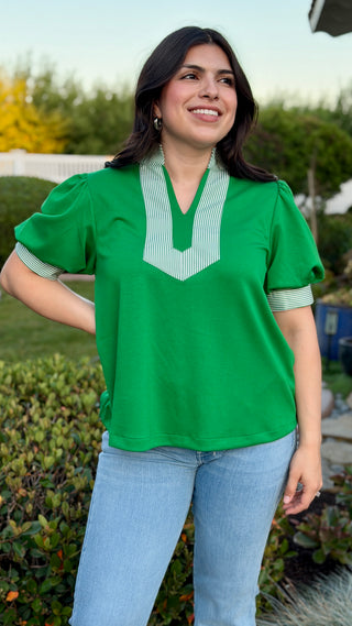 Woman wearing a green blouse with a white collar.