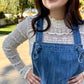Woman wearing blue denim overalls with a white lace long sleeve outdoors