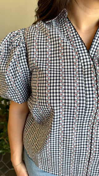 A woman wearing a black plaid blouse with jeans.