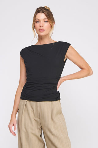 Woman wearing a black top and beige pants on a white background