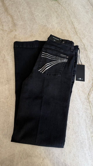 Black jeans with a tag on a beige surface