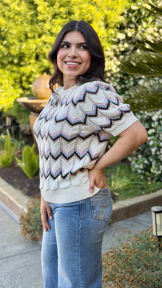 Woman wearing a patterned sweater and jeans.