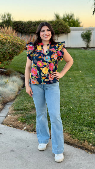 Woman wearing a floral blouse with light wash jeans.
