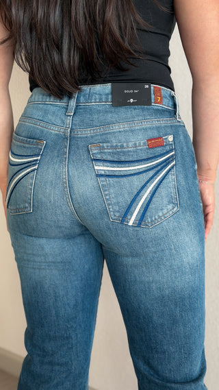 Side-back view of the 7 For All Mankind Dojo mid-rise flare jeans in Bluefern long inseam, showing the fit through the hip and thigh