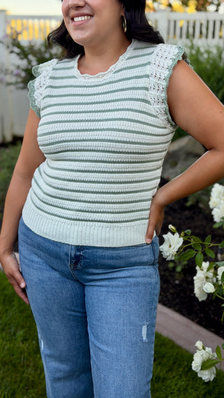 Woman wearing a white and sage striped sleeveless crocheted knit top.