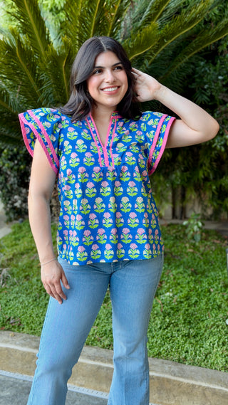 Woman wearing a colorful top with floral pattern and blue jeans.