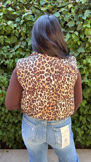 Person wearing a leopard print vest and blue jeans 