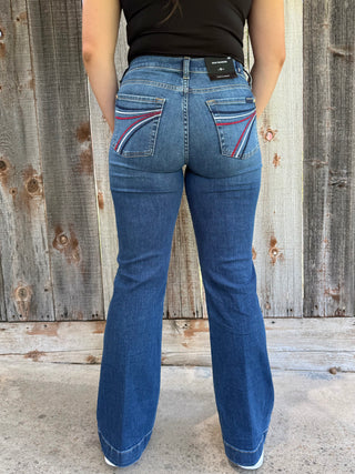 Woman wearing dark wash denim trouser jeans with red, white, and blue stitching on the back pocket