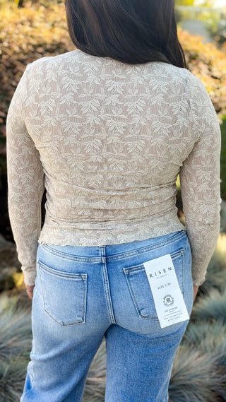Back view of beige lace long sleeve top with ruched fitted waist, worn with light wash jeans