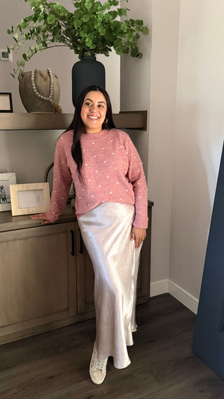 Woman wearing a pink sweater and Ivory satin skirt.