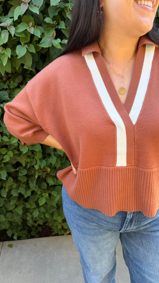 Woman wearing a brown sweater and blue jeans.