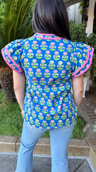 Woman wearing a colorful top with floral pattern and blue jeans.