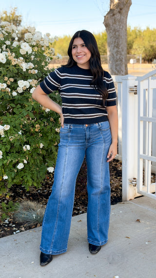 Full-length outfit with navy striped short sleeve sweater top, flare jeans and black boots