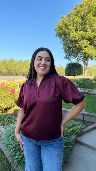 Woman wearing a burgundy v-neck blouse with ruffled sleeves 