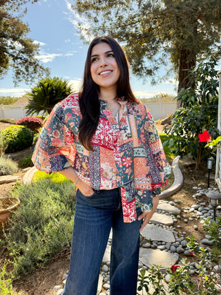 A woman wearing a patchwork 3/4 bubble sleeve blouse with blue jeans.