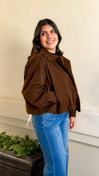 Full-length front view of a women's brown button-front bomber jacket styled with straight-leg jeans