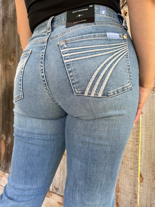 Person wearing light blue jeans with a wooden background