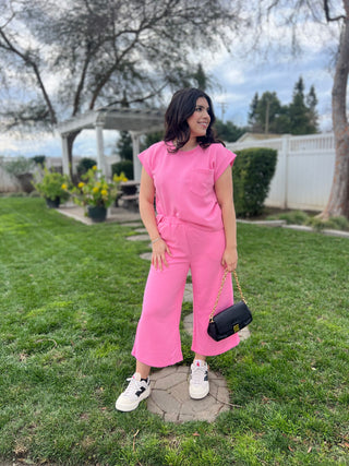 A woman wearing matching bright pink lounging top and pants. 