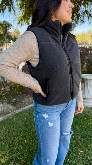 Woman wearing a black vest outdoors with blue jeans
