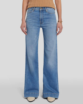 A woman wearing light wash high waisted jeans with a big cuff at the bottom. 